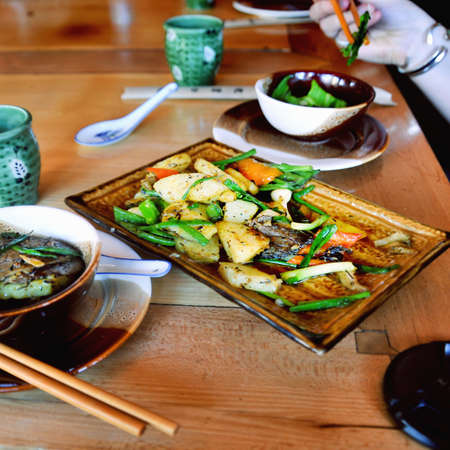 Hand with chopsticks and dinner table in chinese restaurantの写真素材