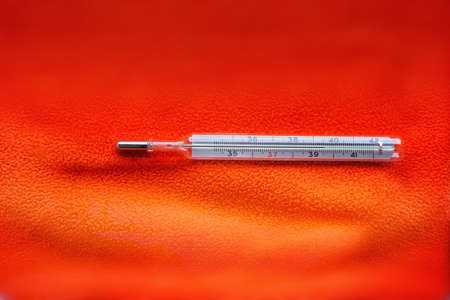 Mercury thermometer showing high tmperature on an orange background.の写真素材