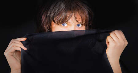 Portrait of young woman with black cloth which covers the lower part of the face.