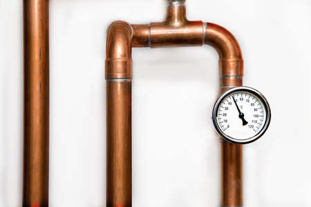 Heating system's cooper pipes with Thermometer on a white wall. Close upの写真素材
