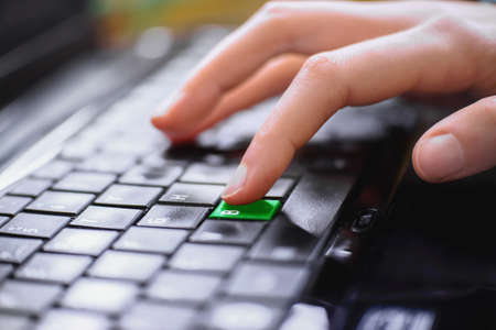 Girl's finger presses the green key letter B on the keyboard of the computer. Close up. Concept...