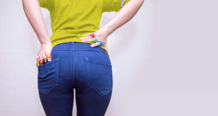 Womanâ€™s buttocks in denim blue jeans and hands with colorful glass rings. Close-up. Fashion,...