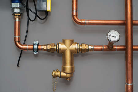 Thermometer and water filter for central heating system on a grey wall in a boiler room. Close up.の写真素材