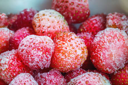 Frozen strawberries in a white plate. Close up.