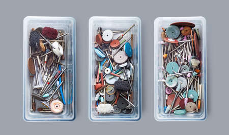 Various grinding and cutting tools in three plastic boxes on a dental prosthetics laboratoryの写真素材