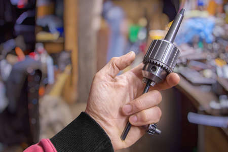 Mens hand with drill chuck in a smith workshop. Close up.の写真素材