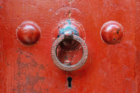 Handle ring on an old red painted door. Close up.の写真素材
