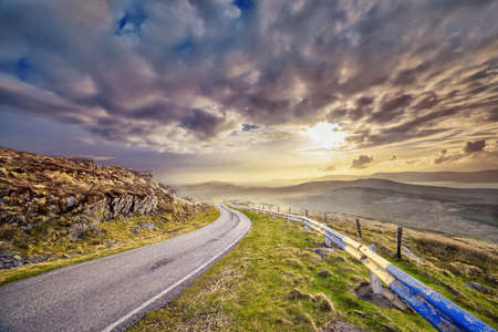 Narrow paved road and a sunset in a county Kerry. Ireland.