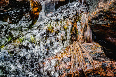 Stones in running water in a mountain river stream. Close view.