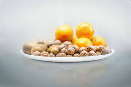 Walnuts, kiwi and oranges on a white plate. Close view.の写真素材
