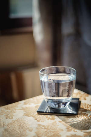 Glass of water on the table with reflections on it. Close view.の写真素材