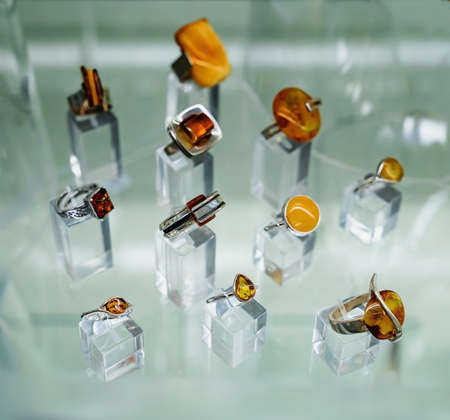 Various silver rings with amber on a glass shelf. Close up.の写真素材