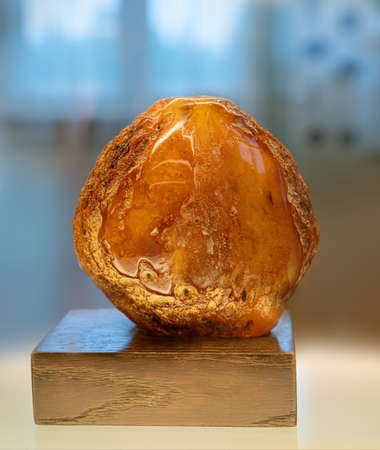 Large piece of amber on a wooden stand . Close up.