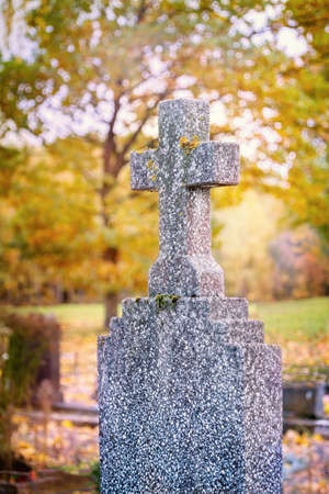 Concrete cross in cemetery in autumn