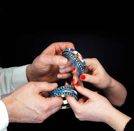 Men's and  woman's hands holding blue bracelets on a black background