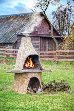 Decorative concrete fireplace with fire and smoke in a village in autumn. Lithuania.の写真素材