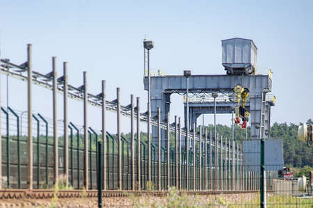 Bridge crane  behind  metal fence on sunny day.