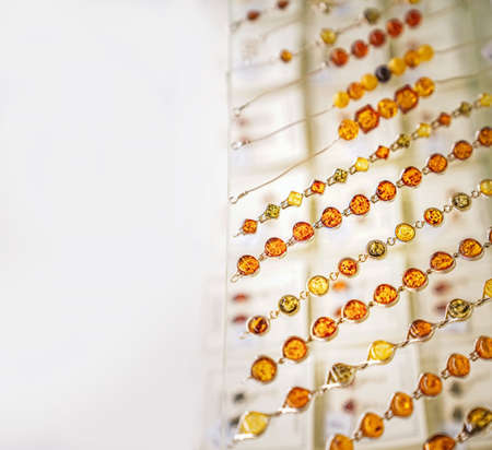 Many various amber necklaces on a glass shelf. Close up. Space for text.の写真素材