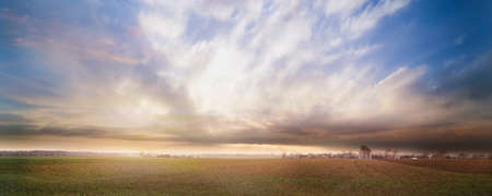Panoramic cloudy and hazy sunset in a village.