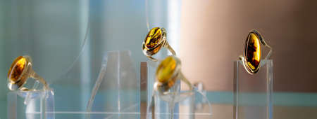 Silver rings with amber on a glass shelf. Close up.