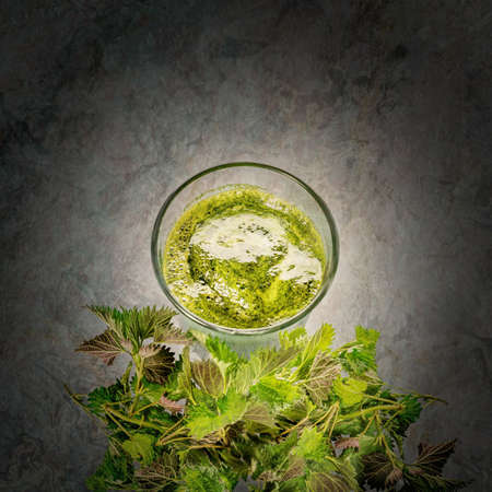 Green raw nettles and a smoothie made of nettles juice in  a glass on a marble background.の写真素材
