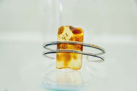 Silver ring with amber on a glass shelf . Close up.の写真素材