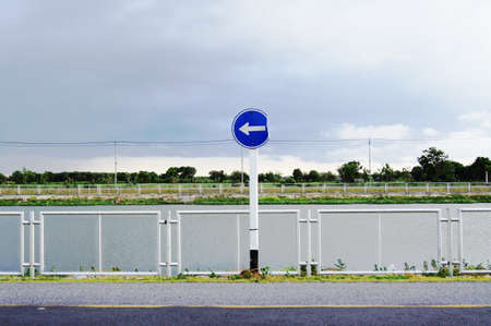 Arrow pointing sign on roadsideの写真素材