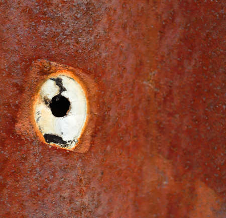 Close up of a hole on rusty metal sheet surfaceの写真素材