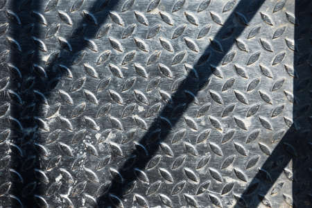 Old checkered steel plates floor with shadow across as abstract backgroundの写真素材
