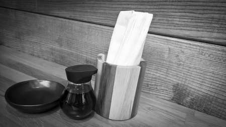 Tissue paper in wooden box with sauce bottle on wooden table in the restaurant - Black and Whiteの写真素材