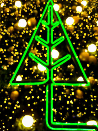 Blurred background of Christmas decoration with green LED Pine tree and golden bokeh lightsの写真素材