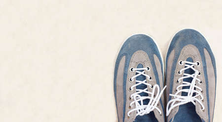 Used Sneakers on light cream color floor background with copy space for text, lifestyle and fashion conceptの写真素材