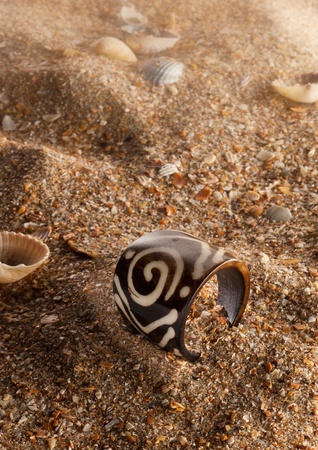 decorated wooden ring accessory on the sea sand の写真素材