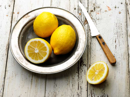 ripe tasty lemon in old steel plate on wooden tableの写真素材