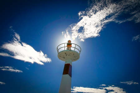 Small metallic lightouse shines under a cloudy skyの写真素材