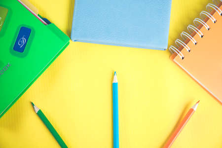 color notepads with pencils on yellow background