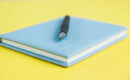 pen on blue notepad on yellow backgroundの写真素材