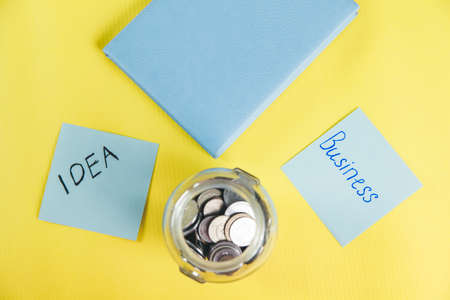 notepad with coins on the yellow deskの写真素材