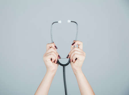 woman hand holding stethoscope on gray backgroundの写真素材