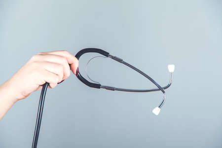 woman hand  stethoscope on the gray background