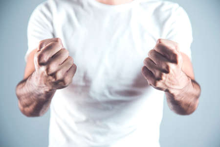 angry man fists on gray wall backgroundの写真素材