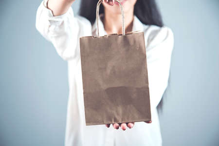 happy woman hand holding a shopping bag on gray backgroundの写真素材