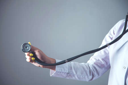 woman doctor hand stethoscope on gray wall backgroundの写真素材