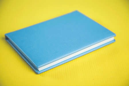 blue notepad on the yellow desk backgroundの写真素材