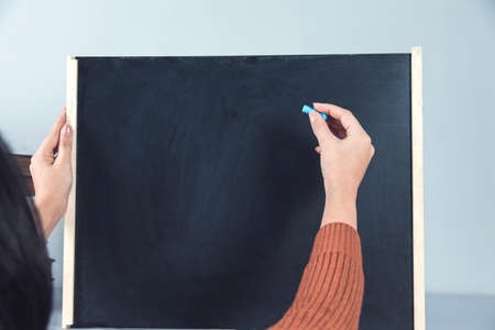 woman hand holding chalk on chalkboard backgroundの写真素材