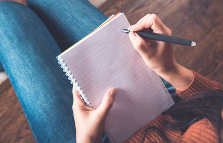 young woman hand holding pen with notepad