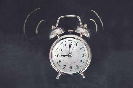 clock on the black chalkboard backgroundの写真素材