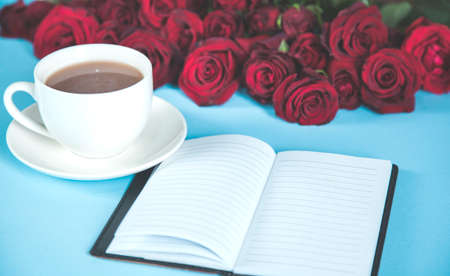 bouquet of red roses with coffee and notepad on deskの写真素材