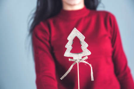 woman hand holding Christmas tree on gray wall background