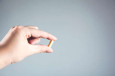woman hand pills on the gray wall background
